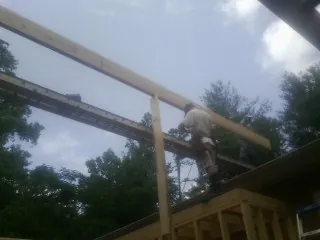 Carpenter setting a ridge beam over a new addition frame — Ice Dam Removal by Roofing Brothers in Orange Park