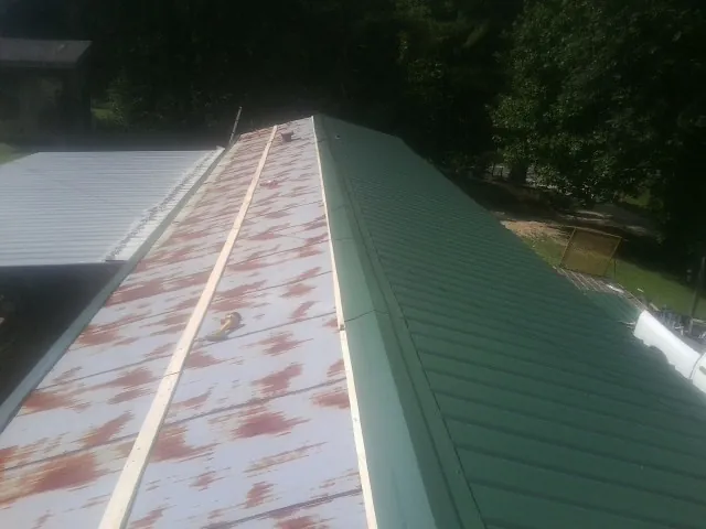 Old rusted panels beside newly installed green metal roofing — Wind Damage Roof Repair by Roofing Brothers in Orange Park