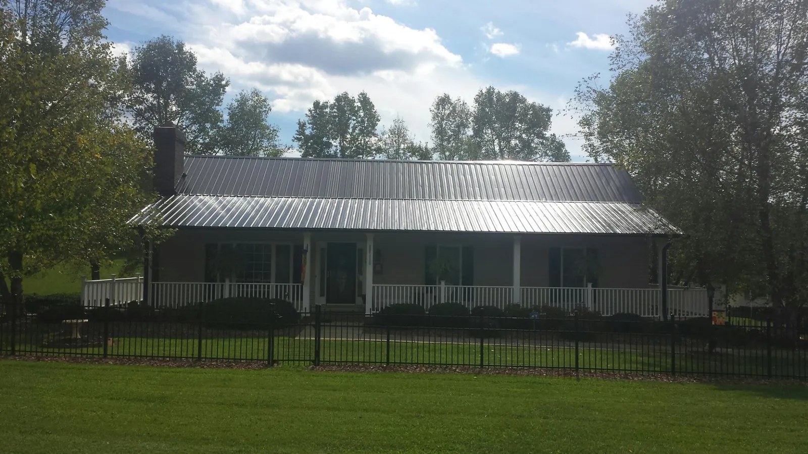 Gray metal roof on a brick ranch with a full width front porch — Gutter Guard Installation work by our crew in Orange Park