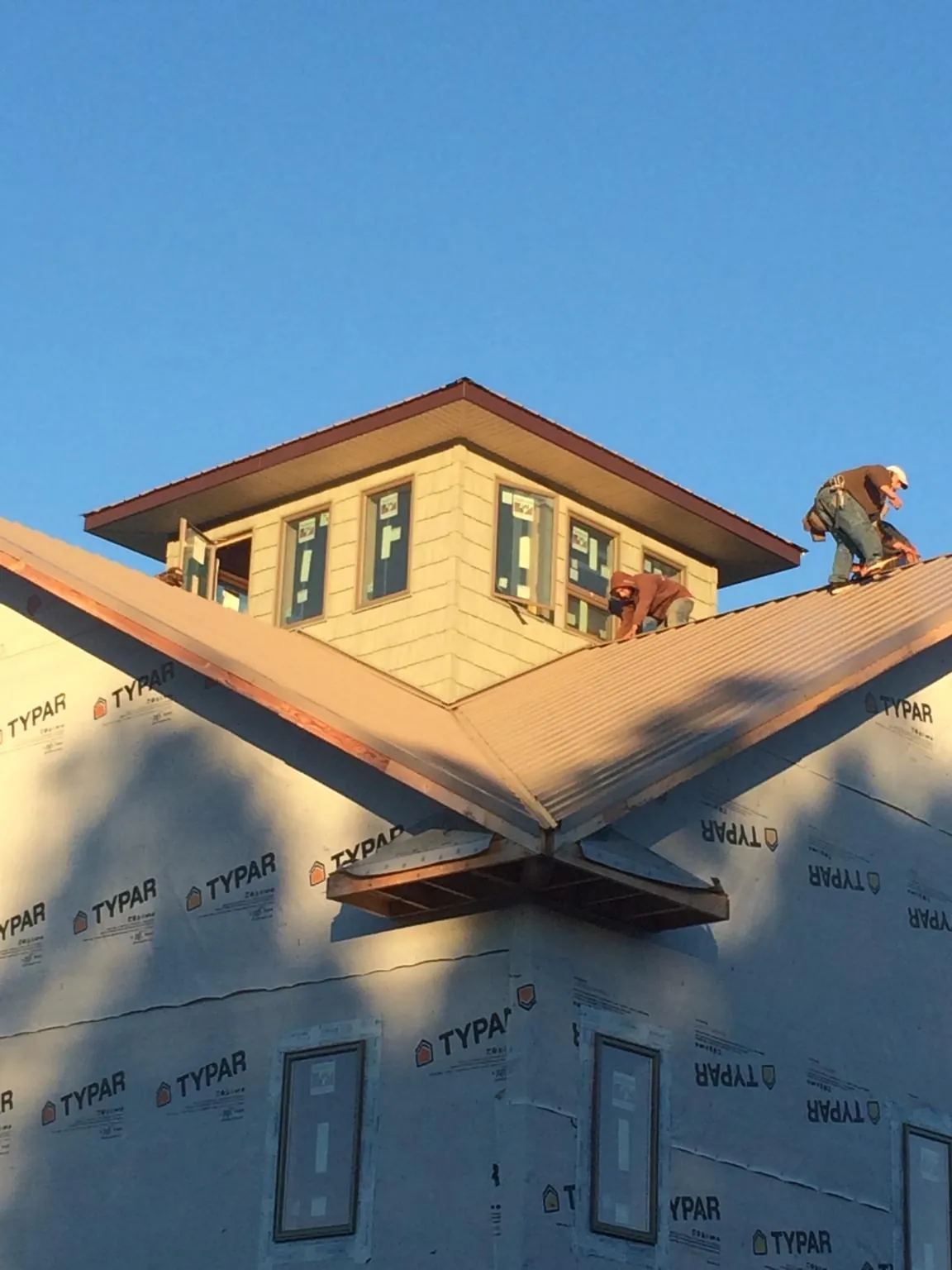 Roofers working around a rooftop cupola on a new metal roof at sunset — Roof Waterproofing in Orange Park by Roofing Brothers